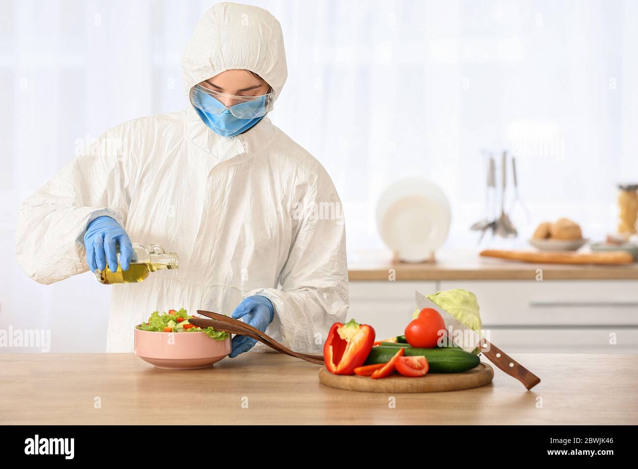 Woman in biohazard suit cooking in kitchen Stock Photo - Alamy