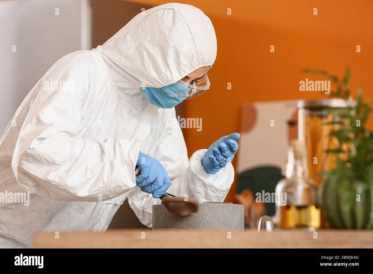 Woman in biohazard suit cooking in kitchen Stock Photo - Alamy