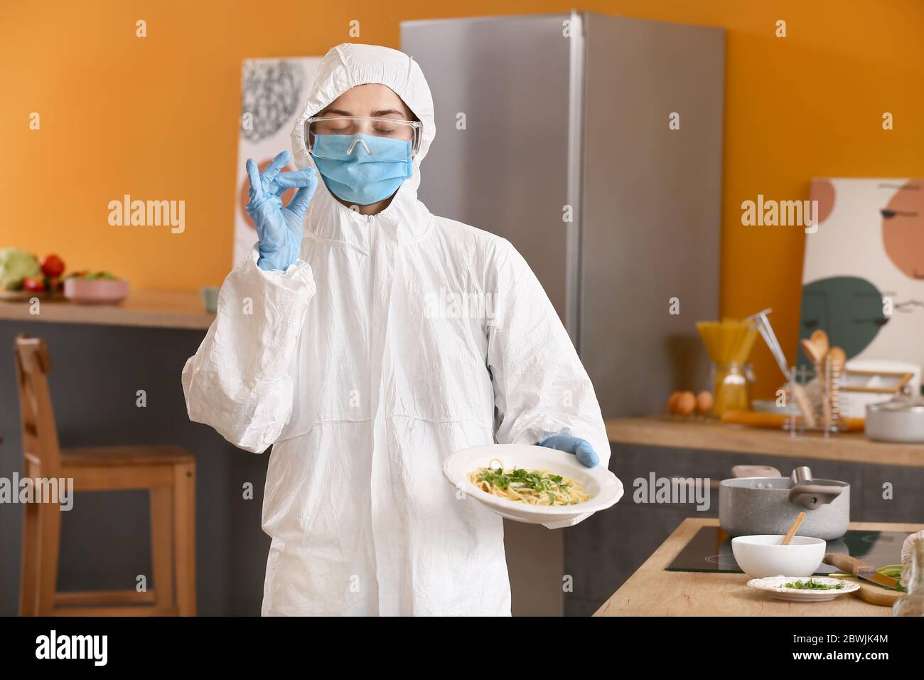 Woman in biohazard suit cooking in kitchen Stock Photo - Alamy
