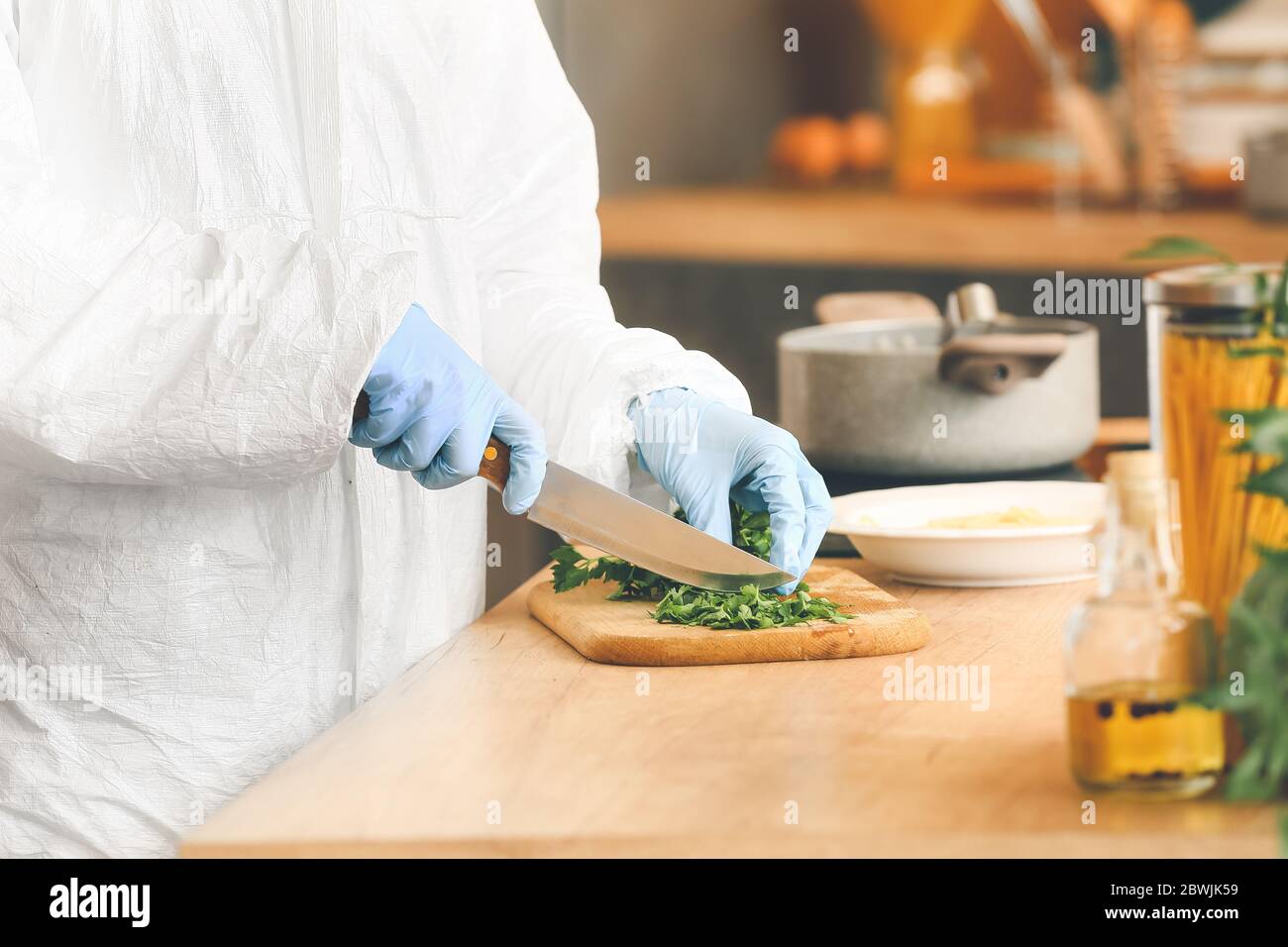 Woman in biohazard suit cooking in kitchen Stock Photo - Alamy