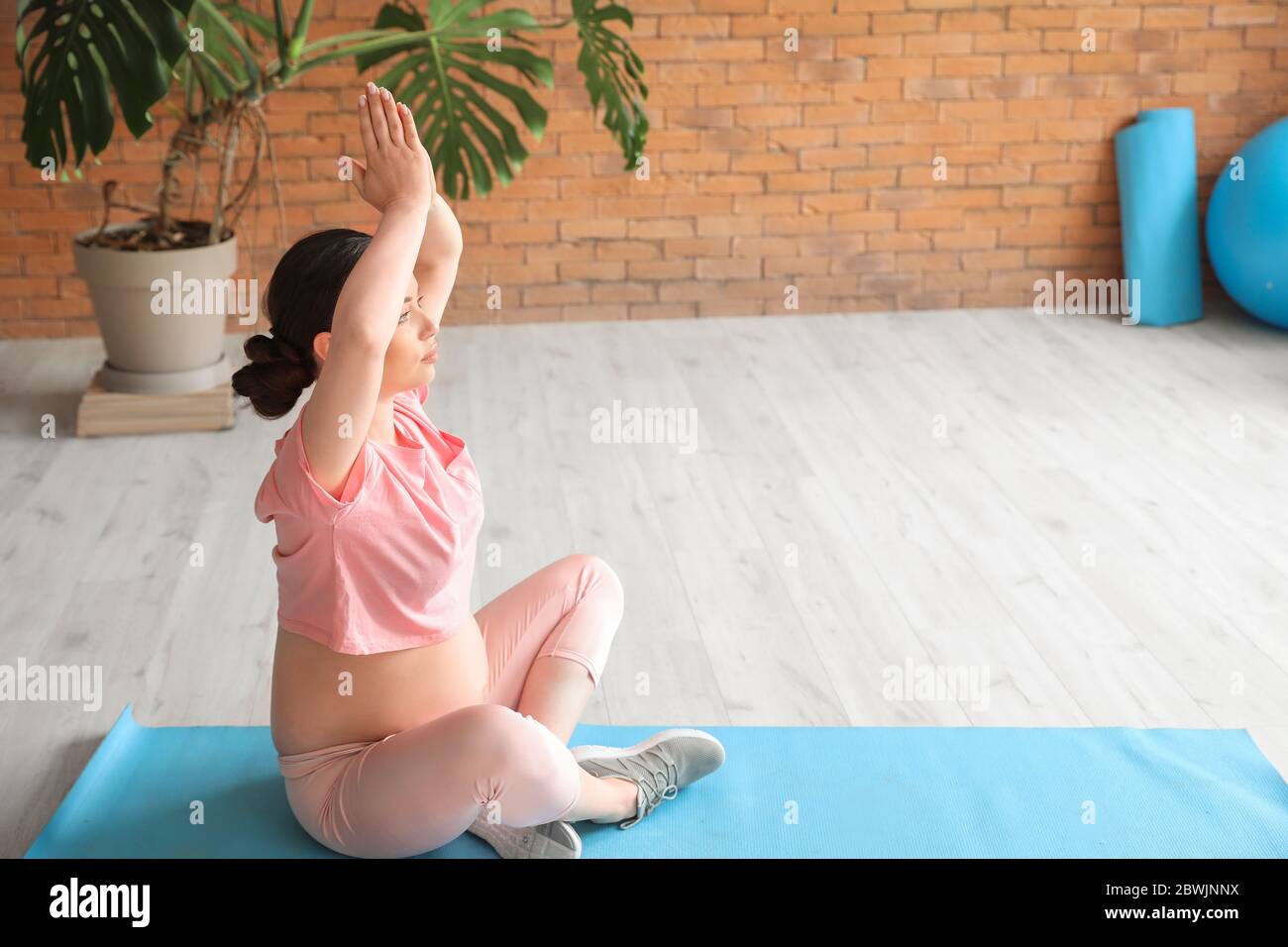 Young pregnant woman and her little son practicing yoga in gym