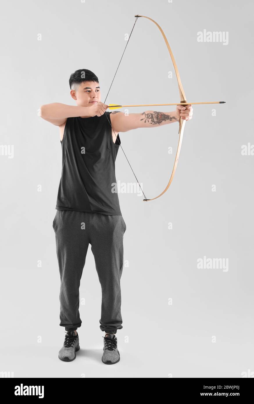 Handsome Asian archer with bow on light background Stock Photo
