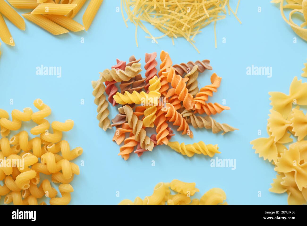 Different uncooked pasta on color background Stock Photo - Alamy