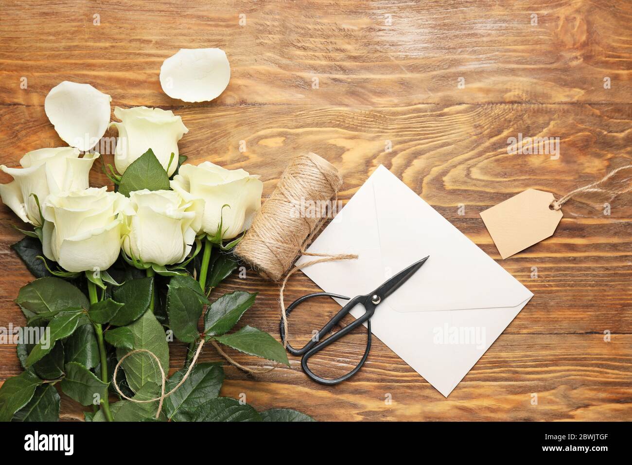 Beautiful white roses, envelope, thread and scissors on wooden ...