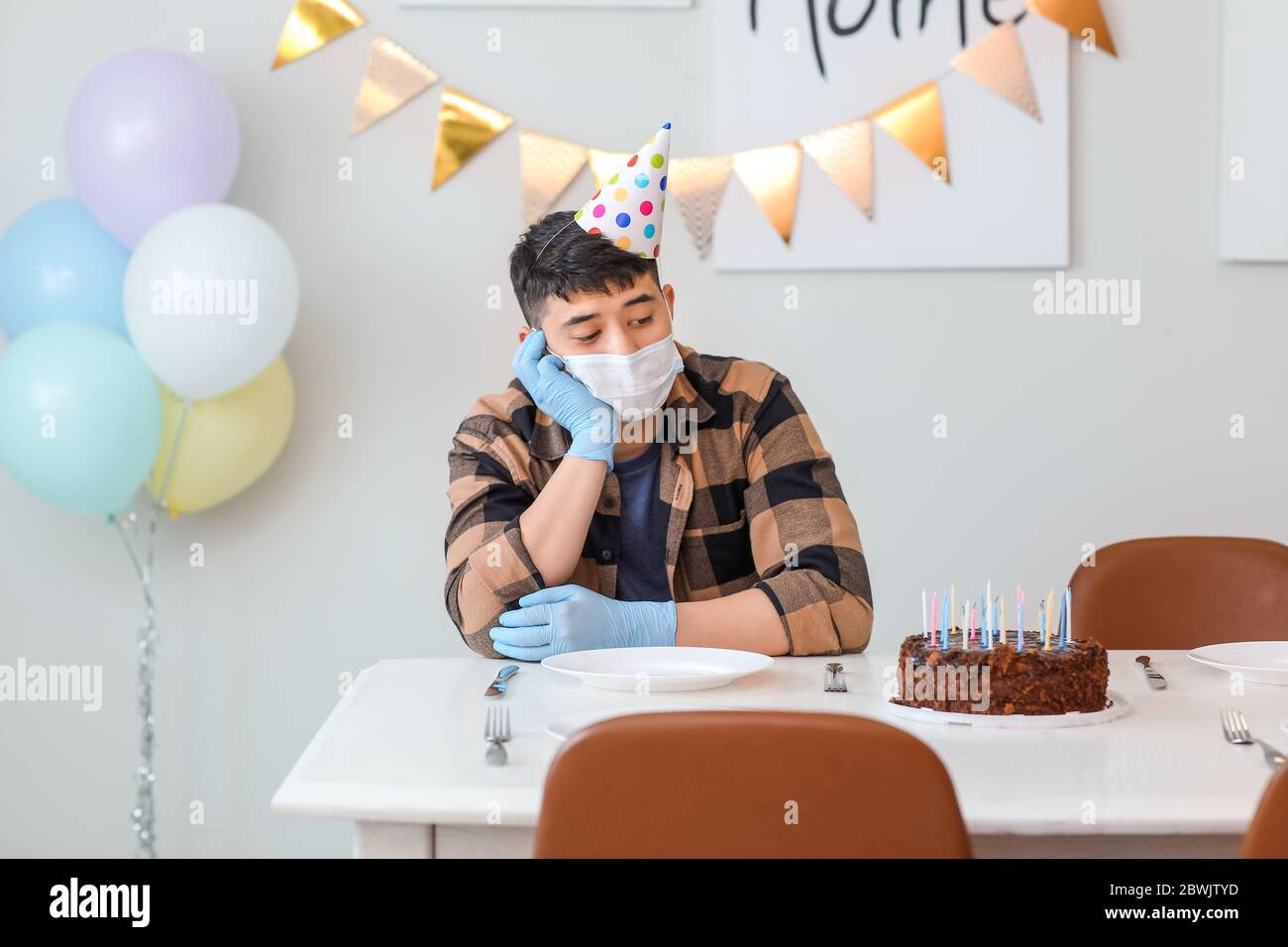 Sad Asian man celebrating Birthday without friends. Concept of epidemic Stock Photo