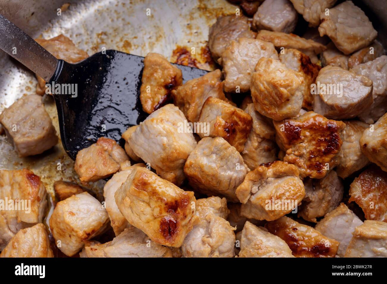 Searing pieces of pork meat are to get roasted aroma for a hearty stew, goulash or ragout, homemade cooking concept, close up, full frame background, Stock Photo