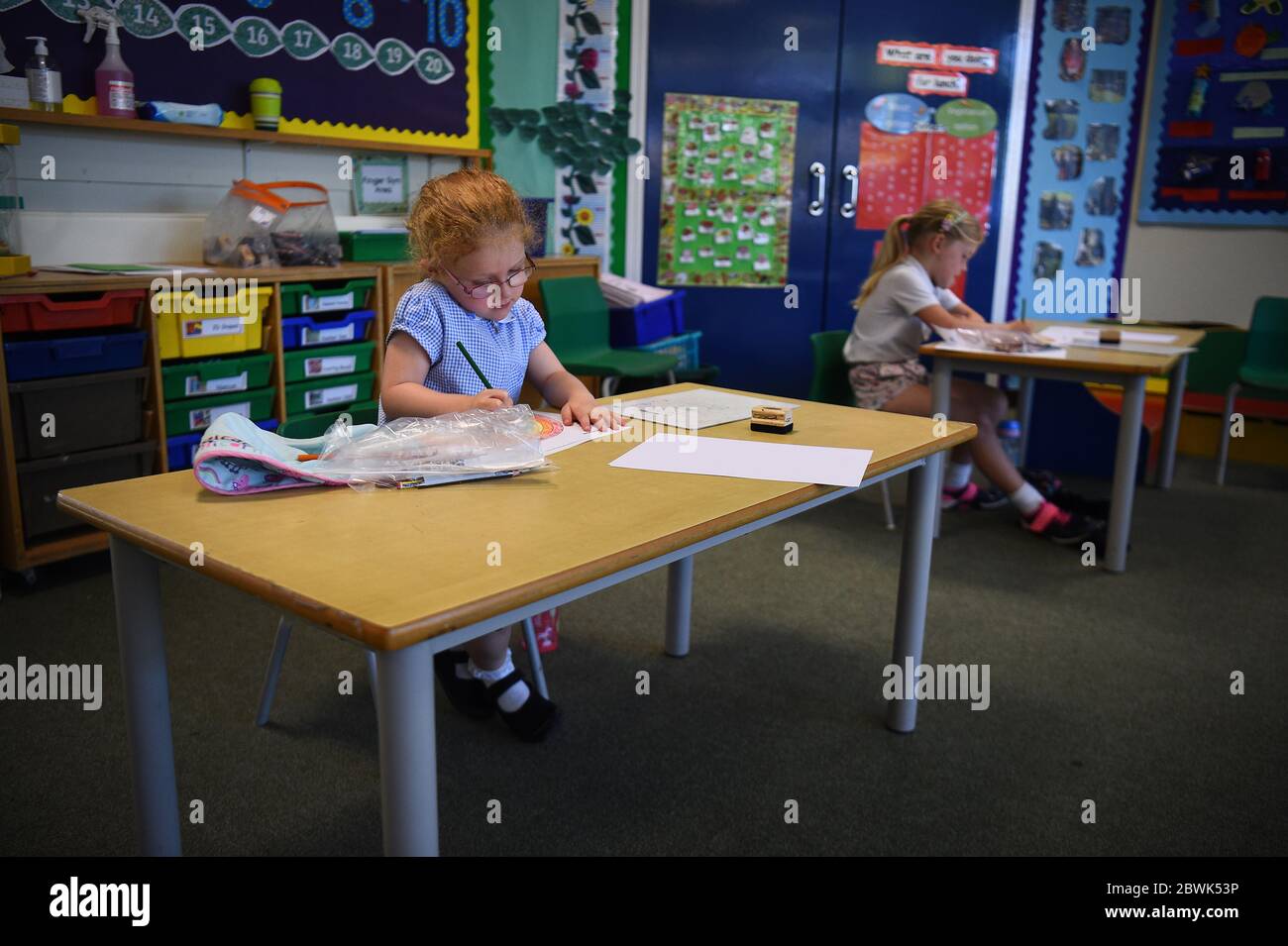 Pupils sit at separate desks at Hiltingbury Infant School in Chandler's Ford, Hampshire, as pupils in Reception, Year 1 and Year 6, begin to return to school as part of a wider easing of lockdown measures in England. Stock Photo