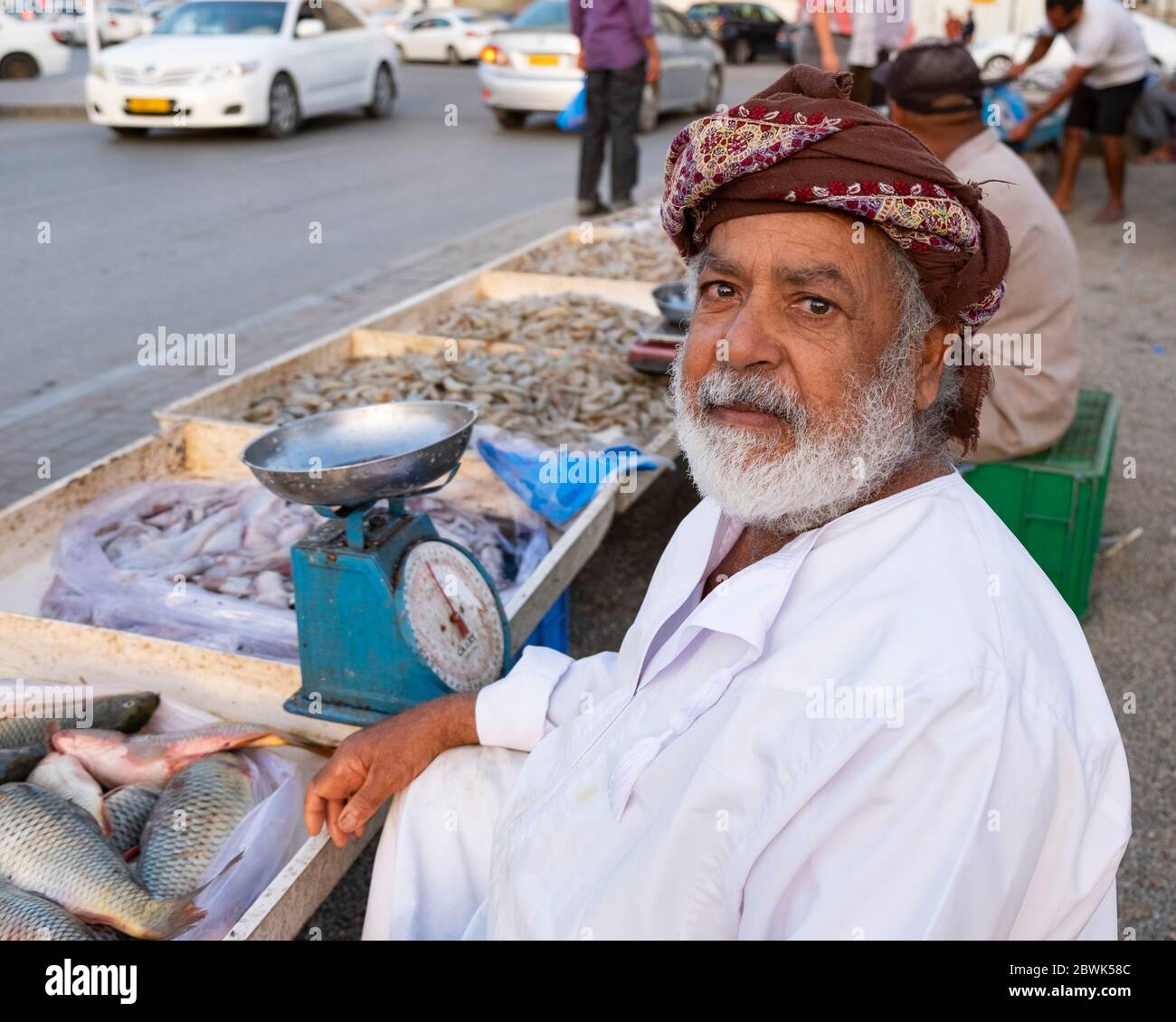 Elderly Omani fishmonger showing a fish at roadside fish market in Muscat, Sultanate of Oman. Stock Photo