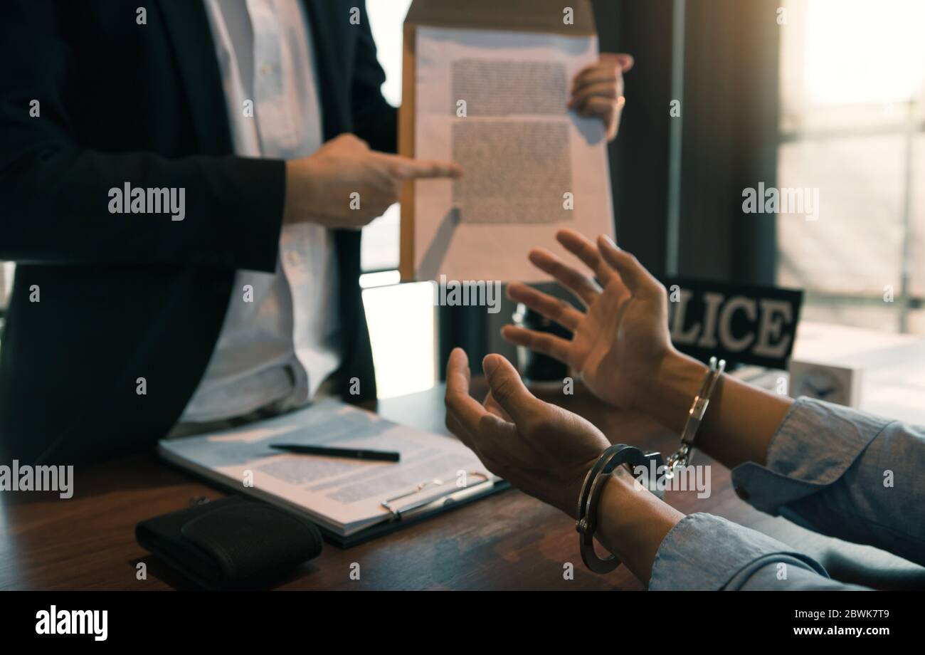 The police officer pointed to the document requesting the arrest of the accused and handcuffed. Stock Photo