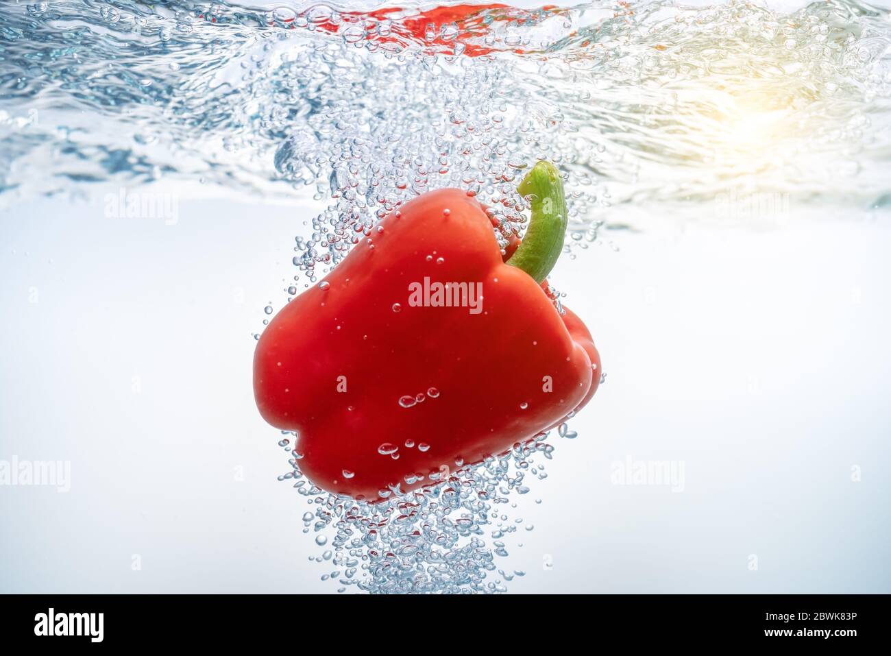 Falling red bell peppers in ecologically clean water through which the