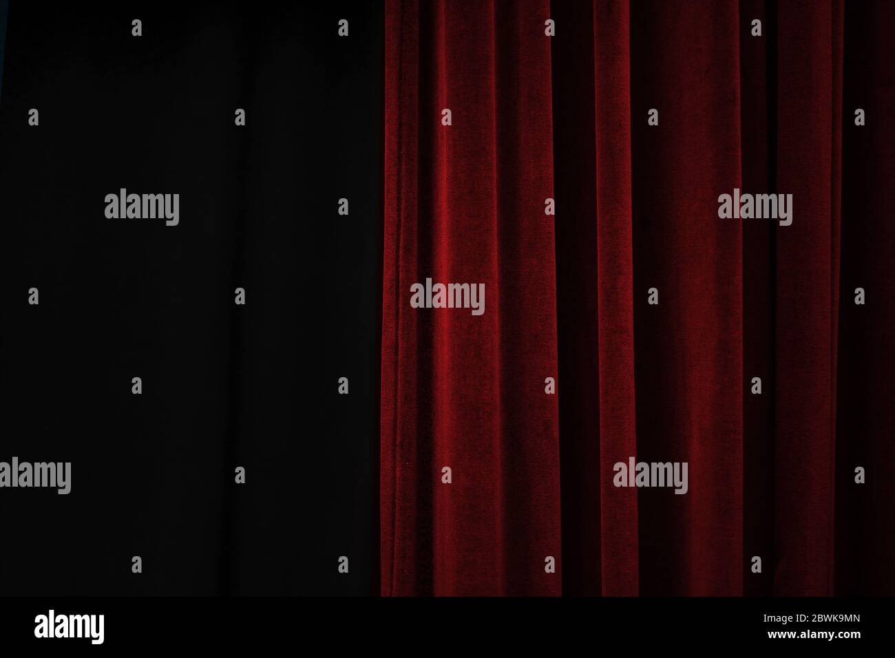 Dark red velvet curtain on one side of a black theatre stage, event ...