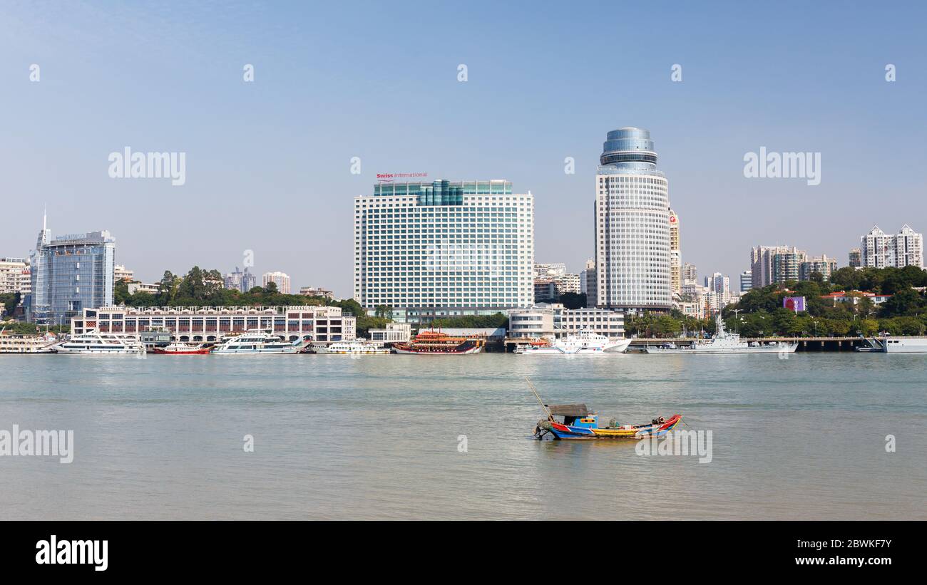 Cityscape of Xiamen with small, colorful boat passing by in the foreground. Symbol for the coexistence of the traditional and the modern. Stock Photo