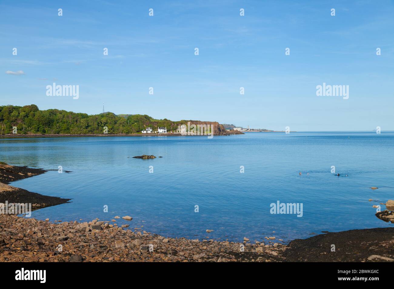 Two people swimming in a flat clam sea at Aberdour, Fife, Scotland. Stock Photo