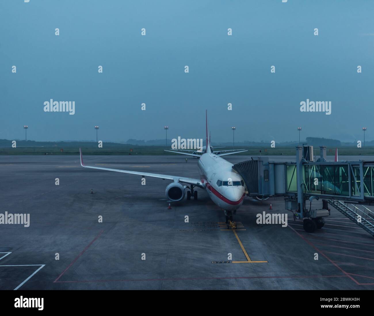 airplane at parking apron view from window of waiting hall of air terminal at dawn on a cloudy day Stock Photo
