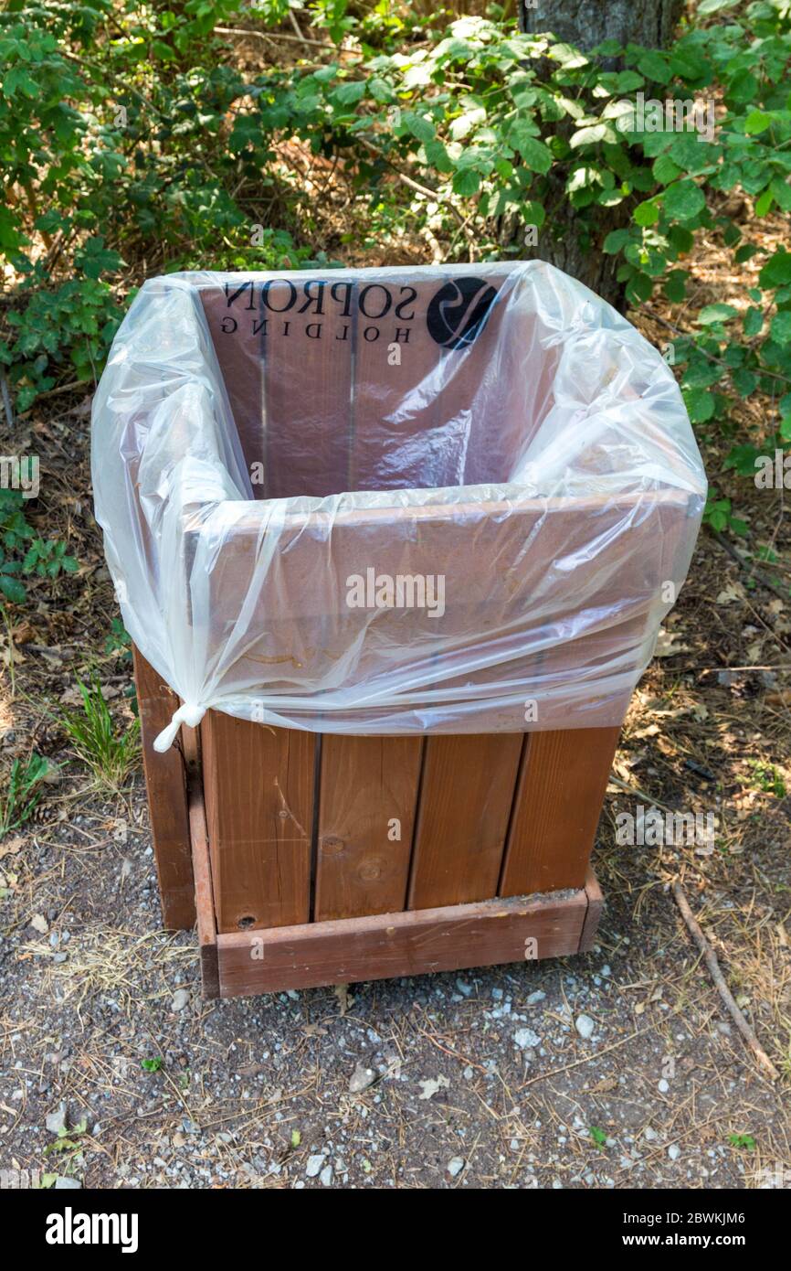 Plastic sack (Sopron Holding) in wooden garbage bin in forest, Sopron, Hungary Stock Photo