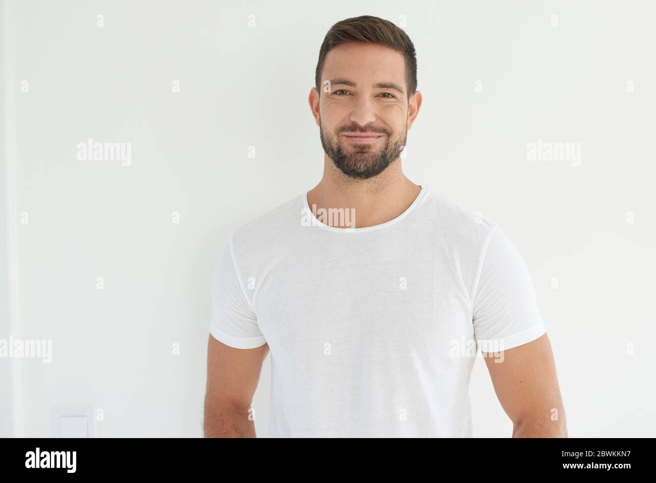Studio portrait of handsome young man wearing white t shirt while ...