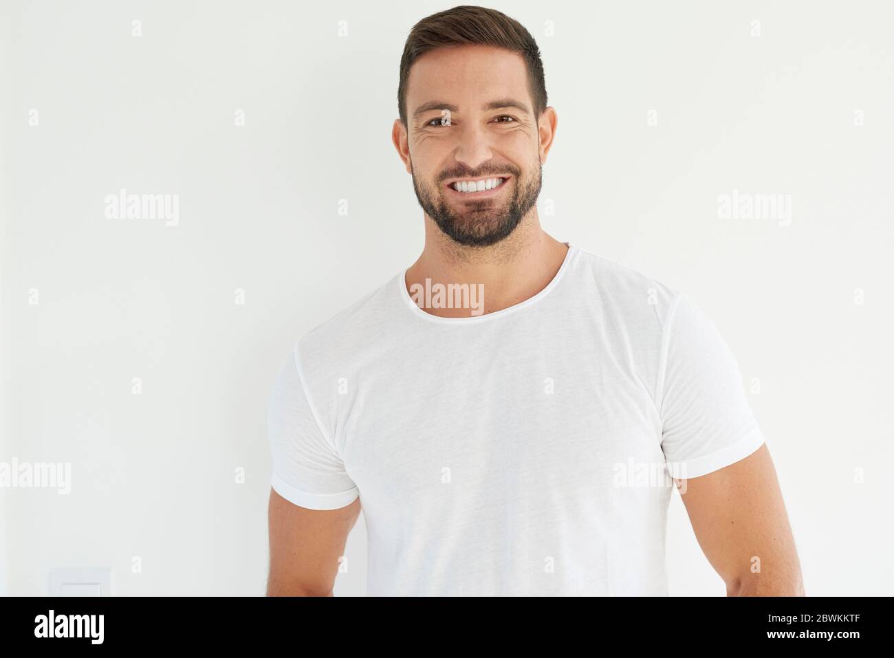Studio portrait of handsome young man wearing white t shirt while ...