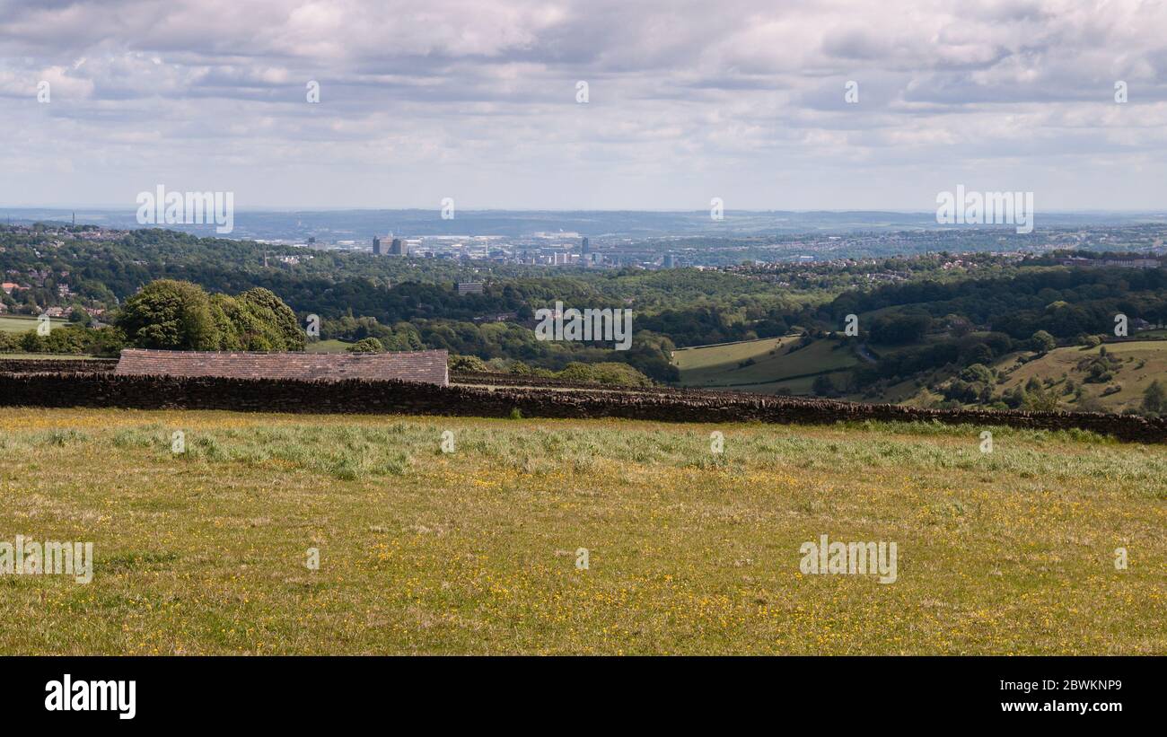 The high rise city centre and low wooded suburbs of Sheffield city are laid out in the Don Valley below the moors of the Peak District. Stock Photo