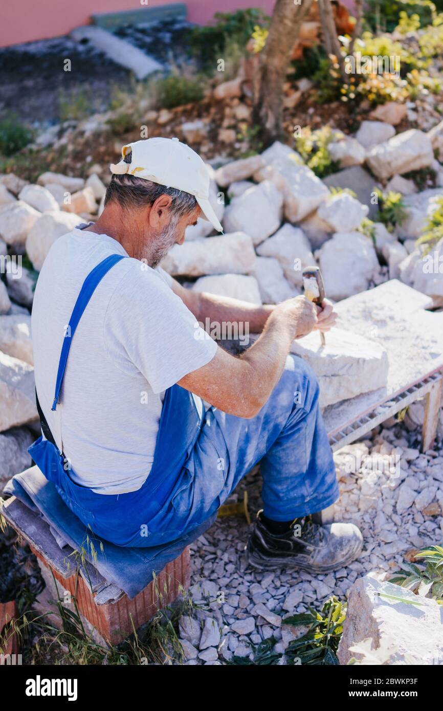 Stone carver working with hammer and chisel Stock Photo - Alamy