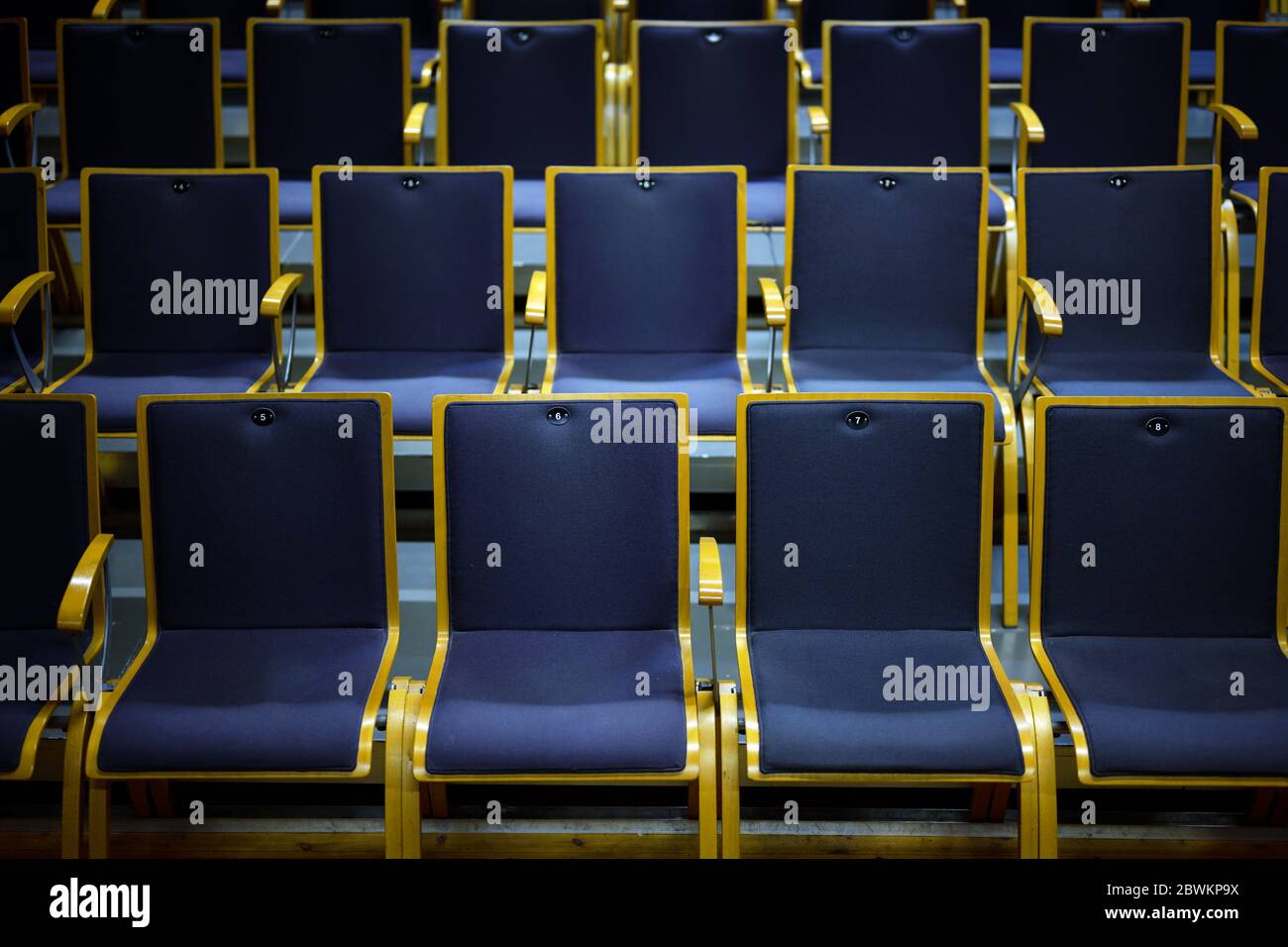 Numbered empty audience seats made of wood and blue upholstery for a