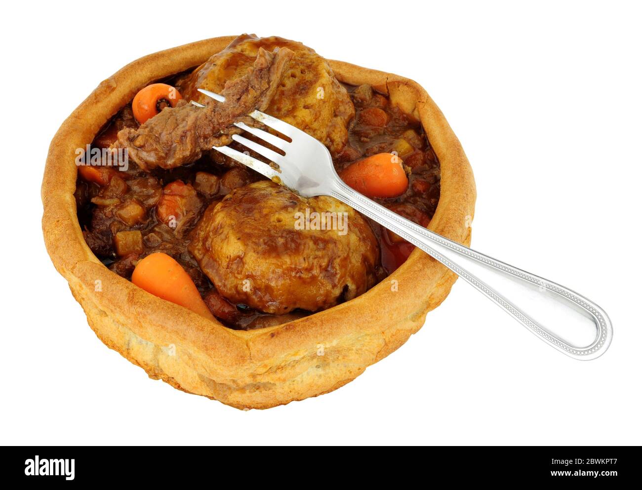 Beef and vegetable stew with dumplings in a large Yorkshire pudding isolated on a white background Stock Photo
