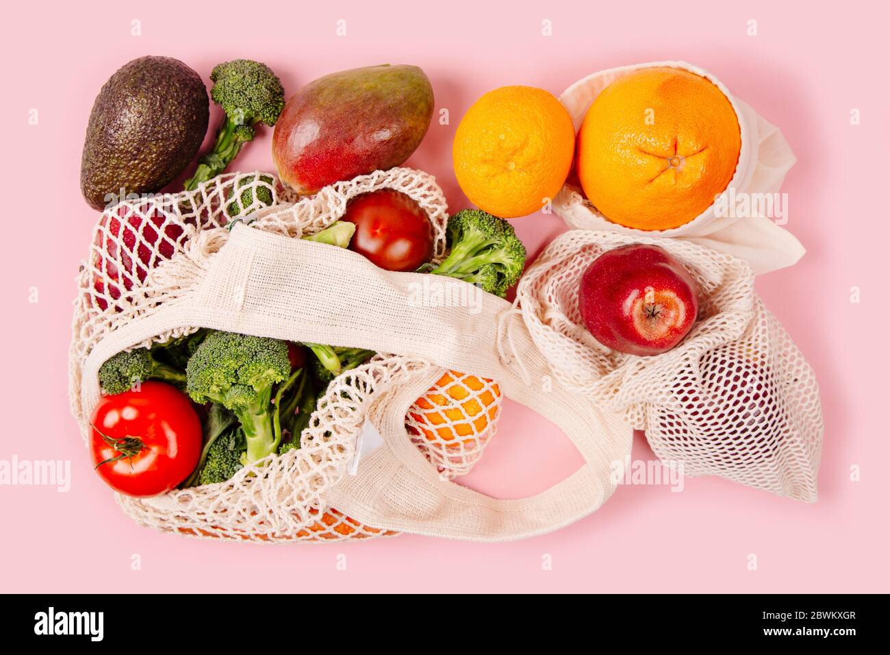 Top view of mesh shopping bag with organic eco vegetables on pink ...