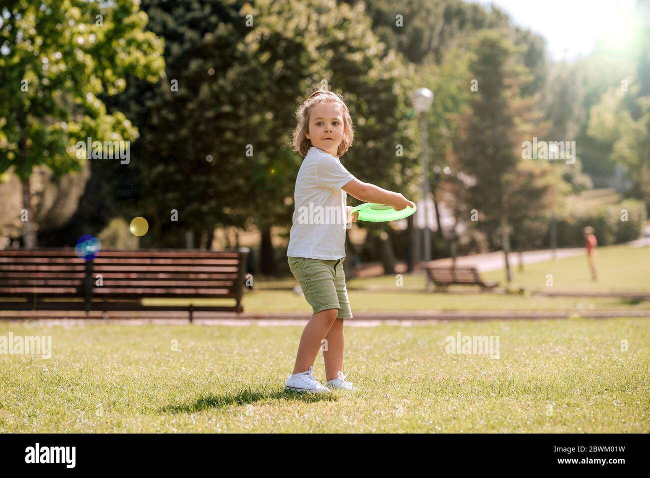 blond boy plays frisbee in the park on a sunny summer day. play abroad