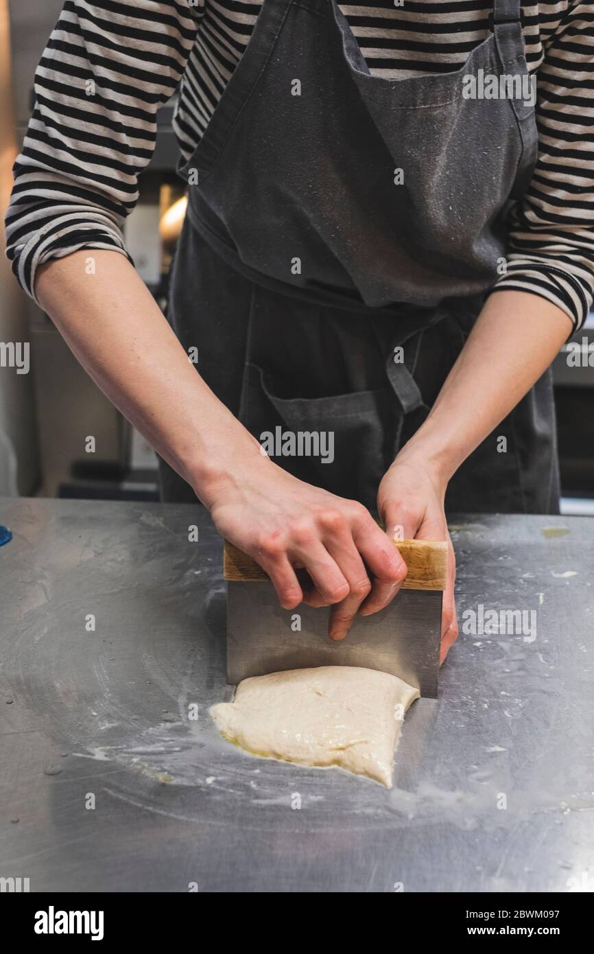 Artisan bakery making special sourdough bread, baker divind dough into loaves for baking. Stock Photo