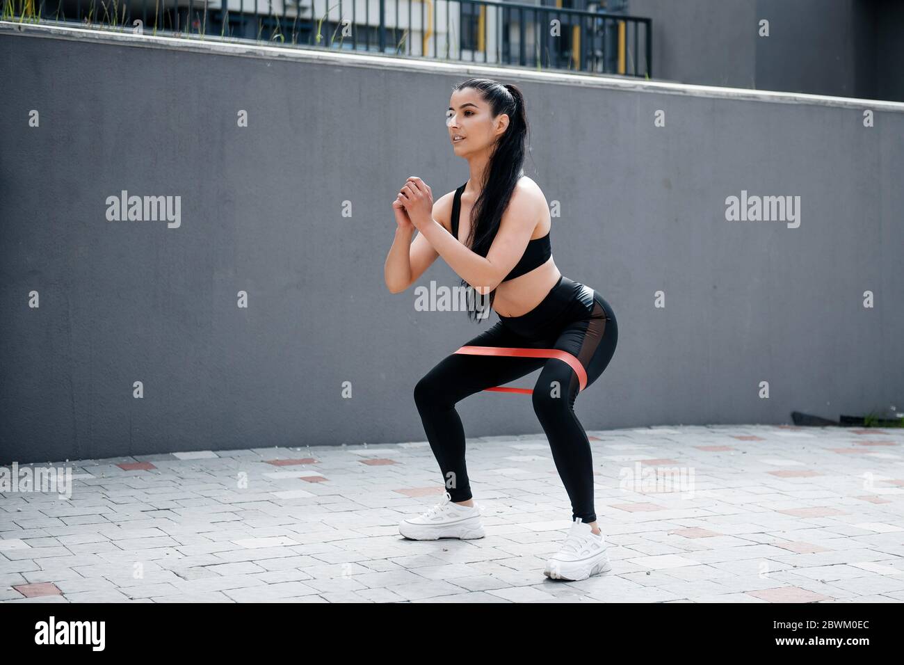 Young sporty fit woman with long ponytail in sportswear squats with fitness  elastic band on legs. Sports concept, healthy lifestyle Stock Photo - Alamy