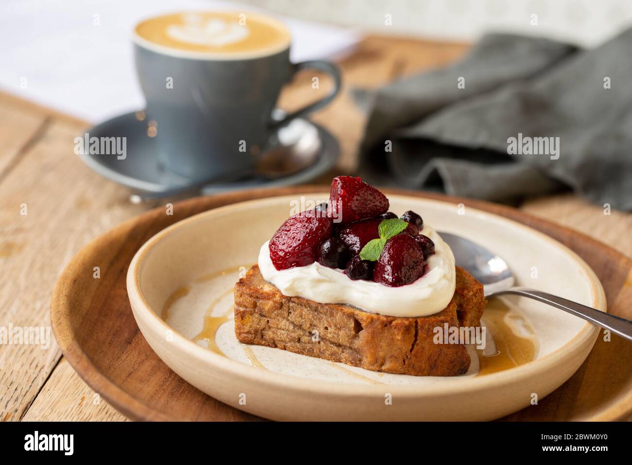 High angle close up of banana bread topped with yoghurt and mixed berries in a cafe. Stock Photo