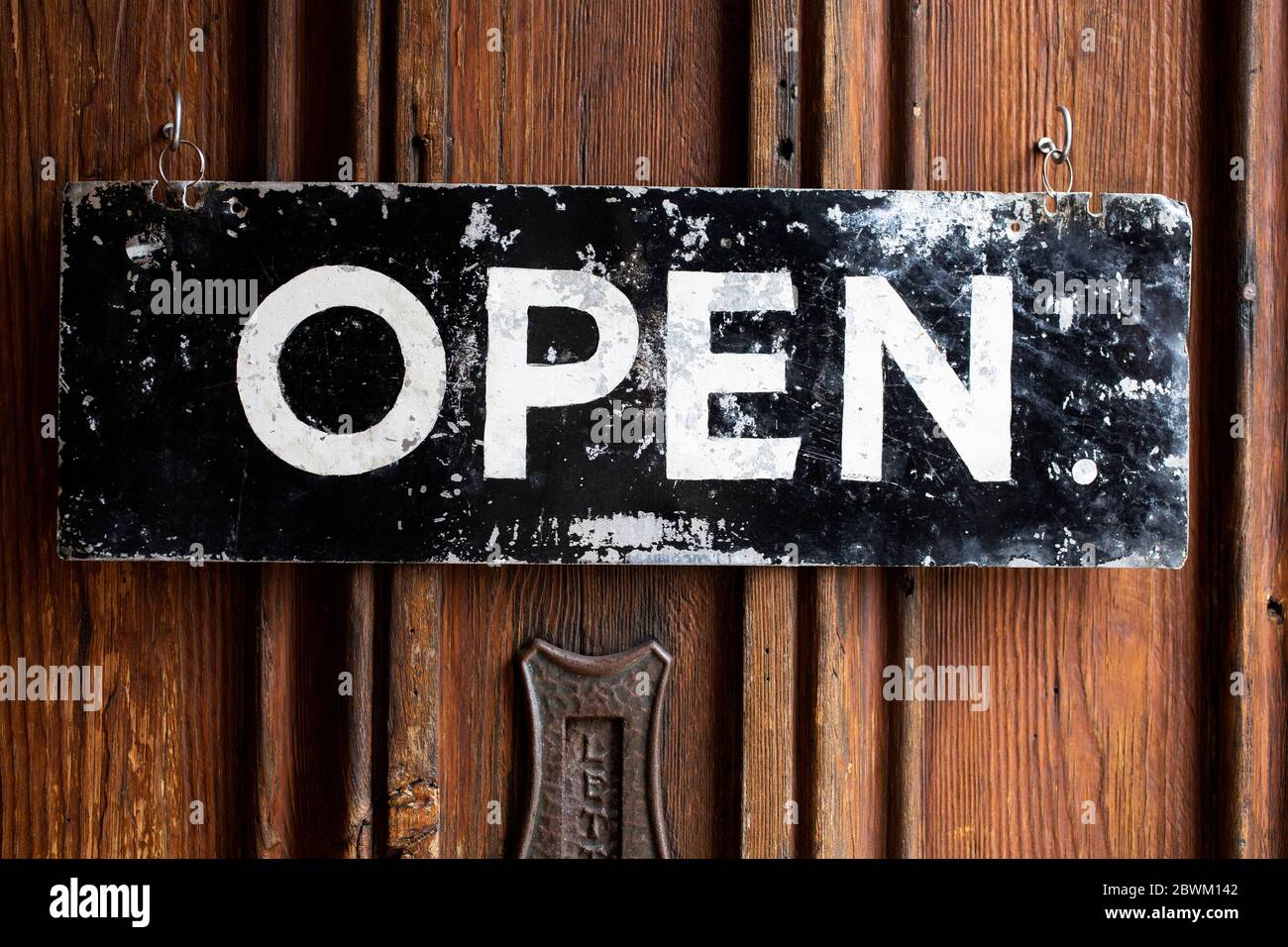 Close up of black and white open sign on wooden door of a cafe Stock