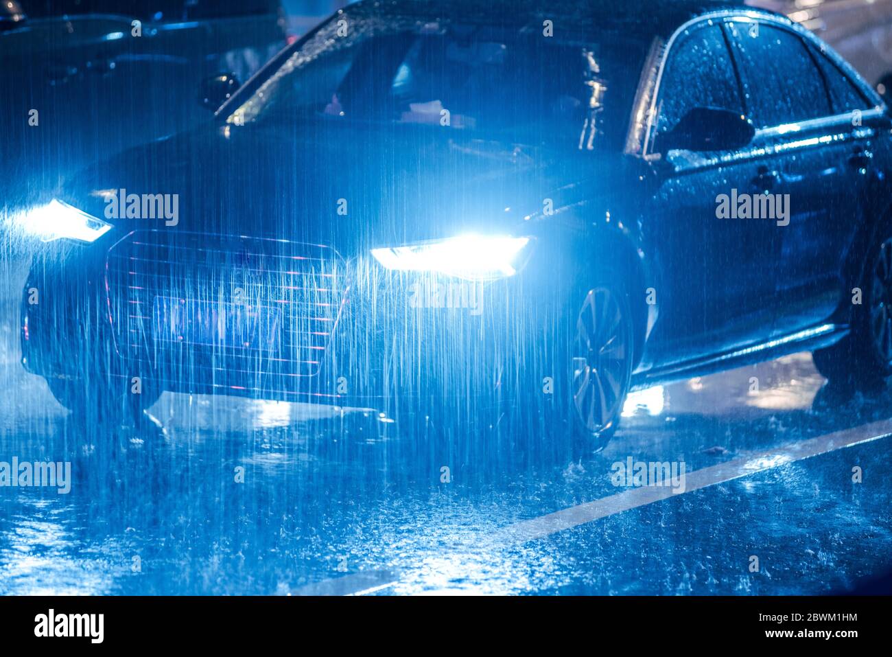 Cars driving on wet road in the rain and colored lights reflected on ...