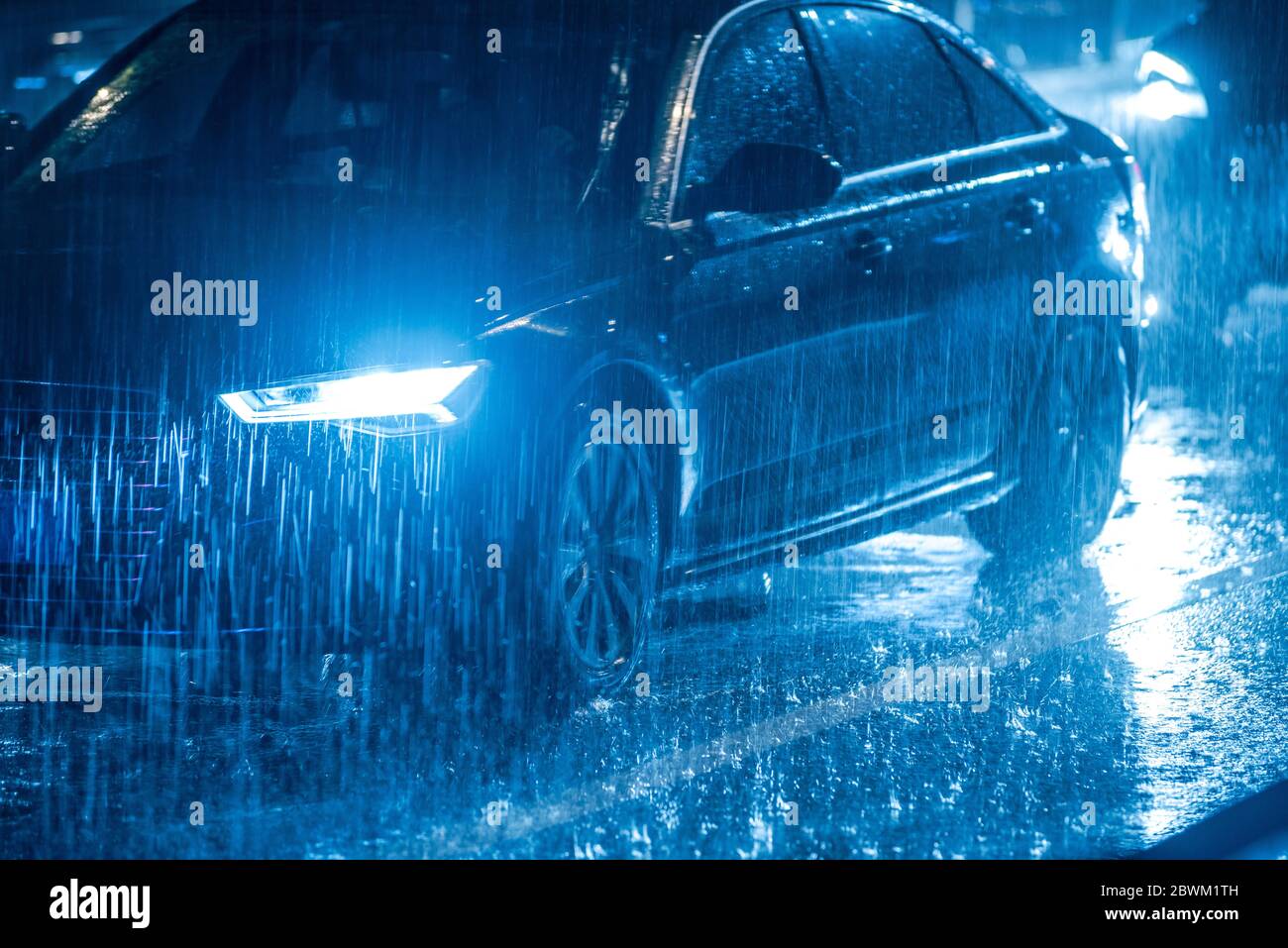 Cars driving on wet road in the rain and colored lights reflected on ...