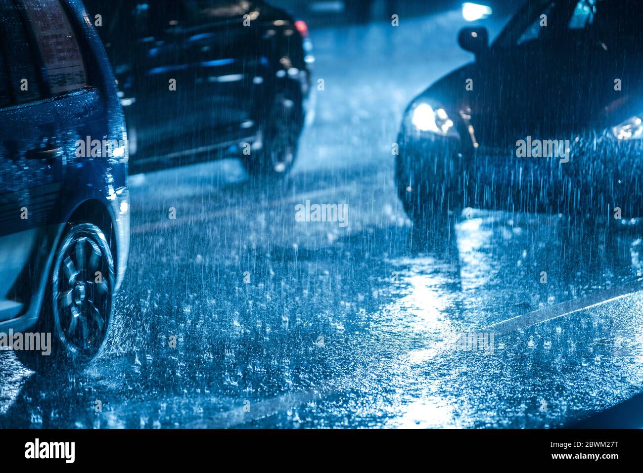 Cars driving on wet road in the rain and colored lights reflected on ...