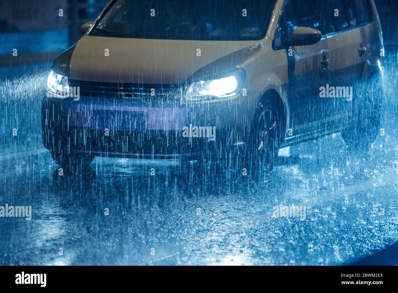 Cars driving on wet road in the rain and colored lights reflected on ...
