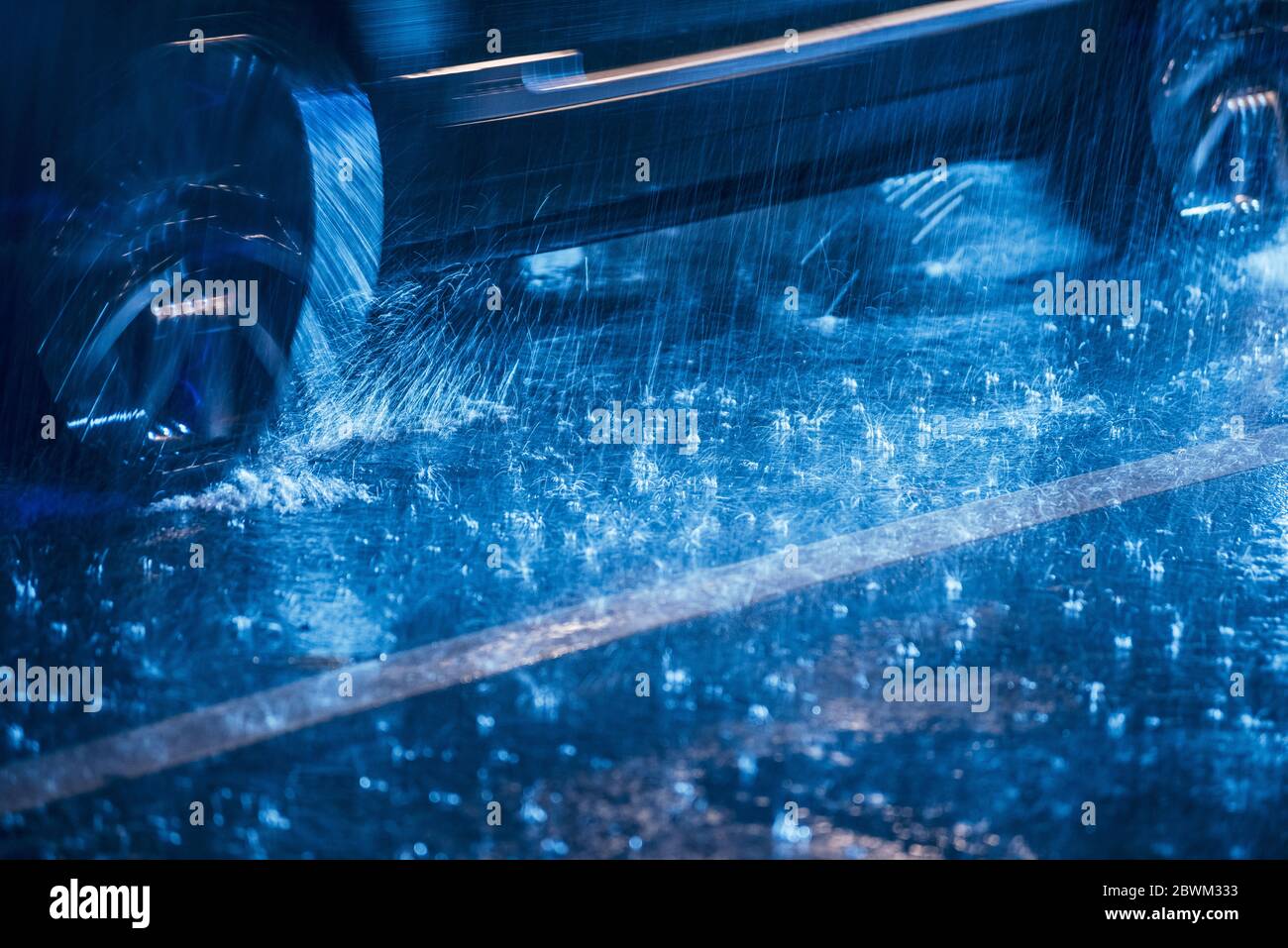 Cars driving on wet road in the rain and colored lights reflected on ...