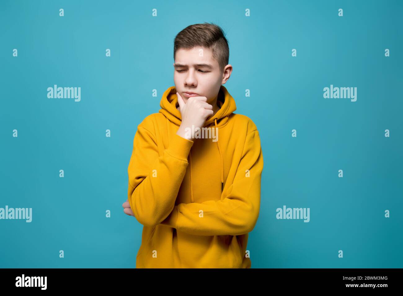 A young man in a sweatshirt looks doubtfully at an imaginary object to his left Stock Photo