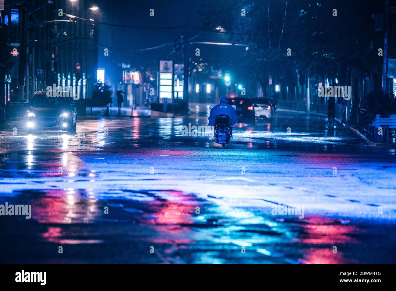 Cars driving on wet road in the rain and colored lights reflected on