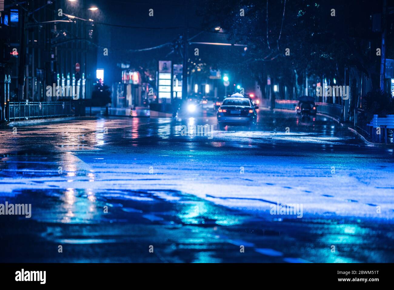Cars driving on wet road in the rain and colored lights reflected on