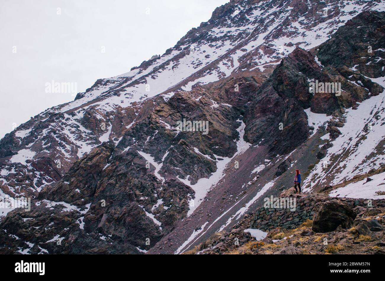 A young adult woman in her 20s trekking in the Andes Mountains and looking away. Stock Photo