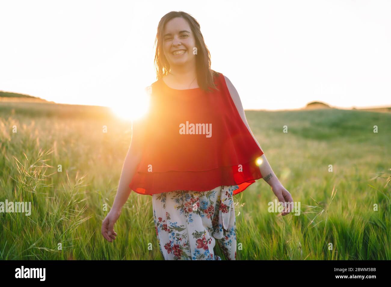 Cute girl in red dress, laughing with joy outdoors in the springtime sunset .  Stock Photo