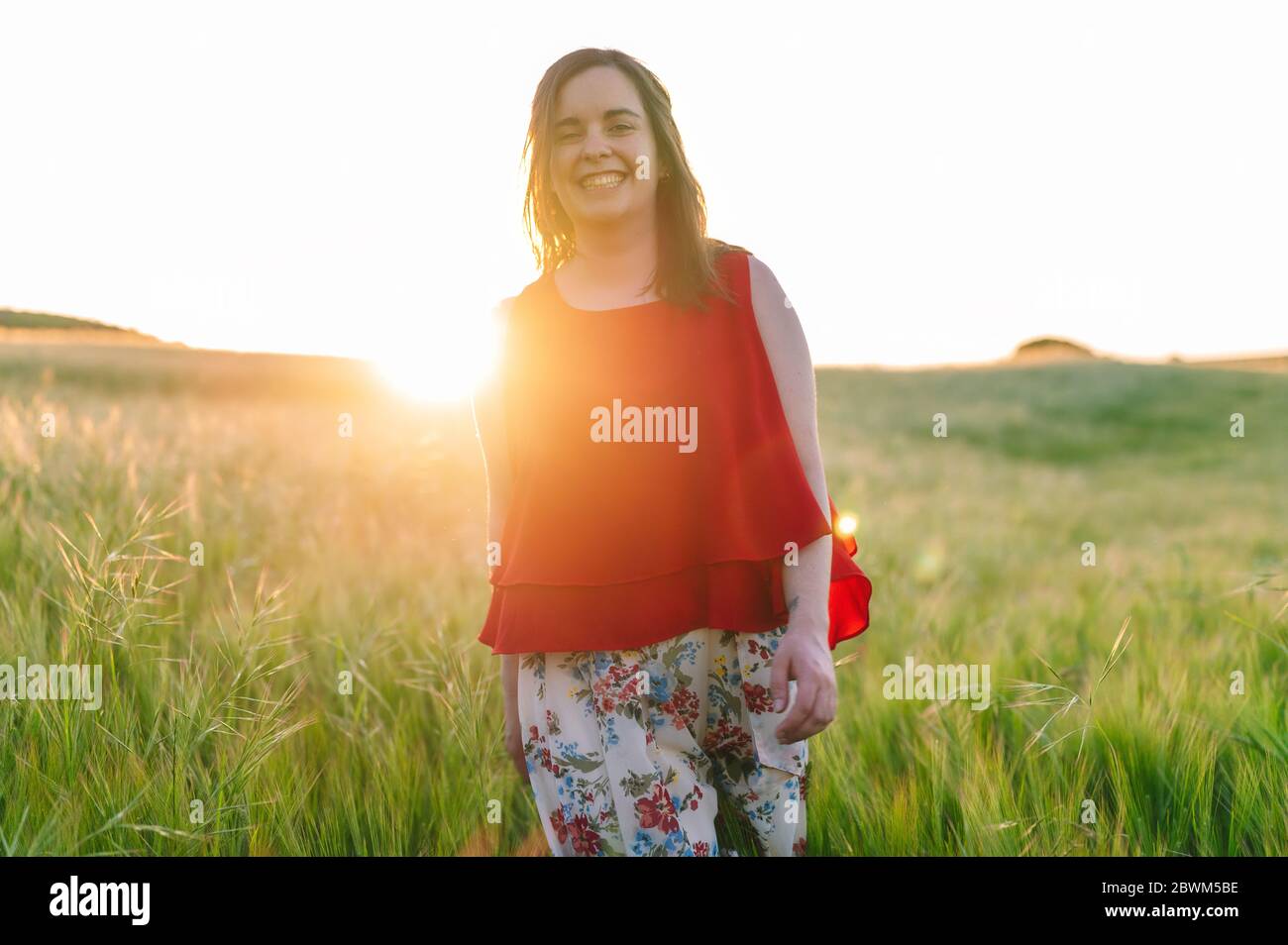 Cute girl in red dress, laughing with joy outdoors in the springtime sunset .  Stock Photo