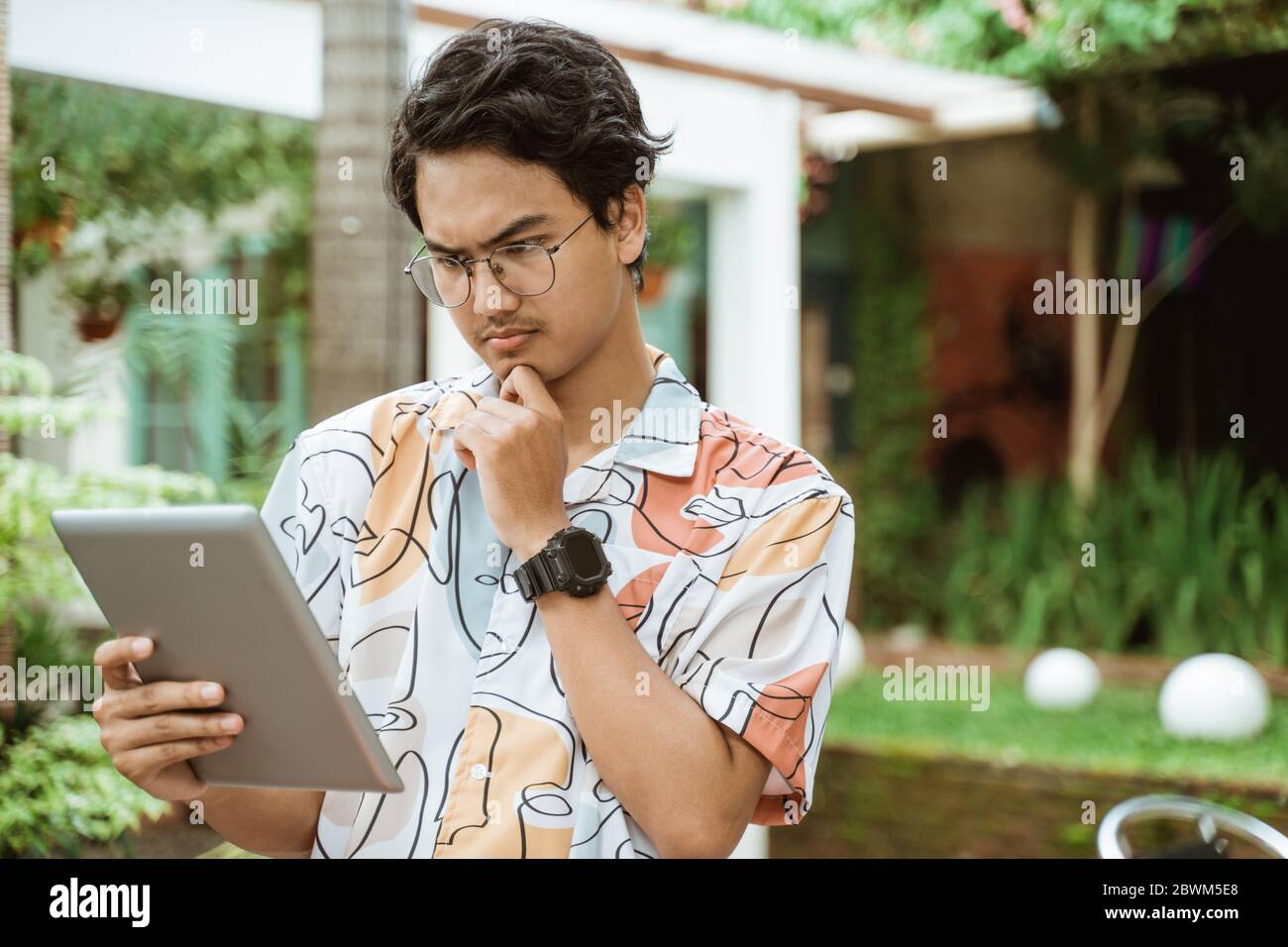 Serious bespectacled man using a tablet pc for work outdoor Stock Photo