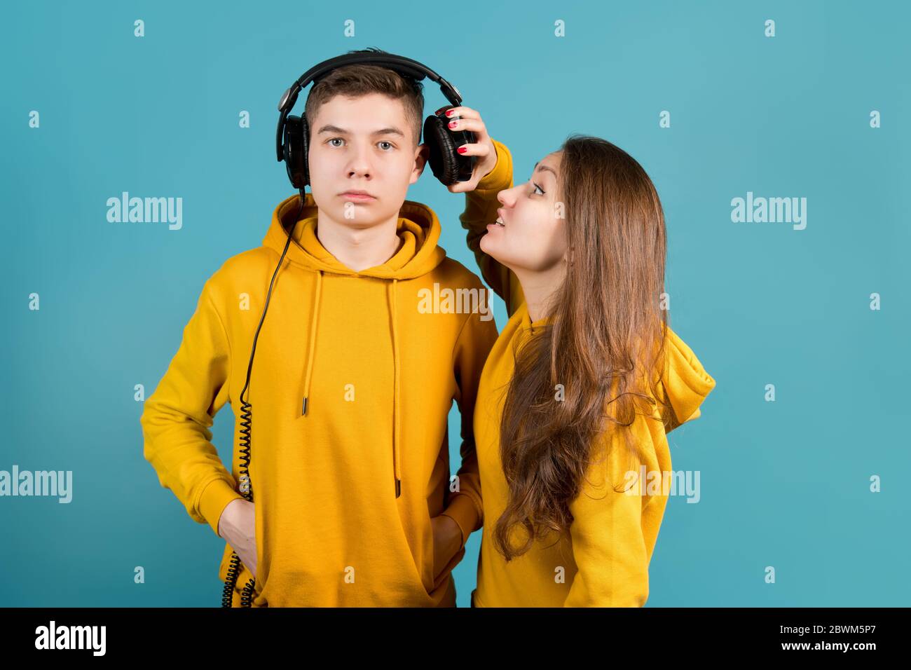 the girl pushes one earphone away from the guy in order to tell him something in the ear Stock Photo