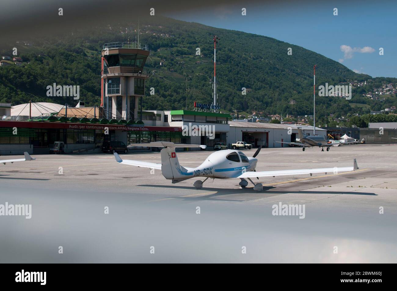 Agno, Ticino, Switzerland - 21st May 2020 : View through the gate of the Lugano-Agno airport in Switzerland with a small airplane parked in front of i Stock Photo