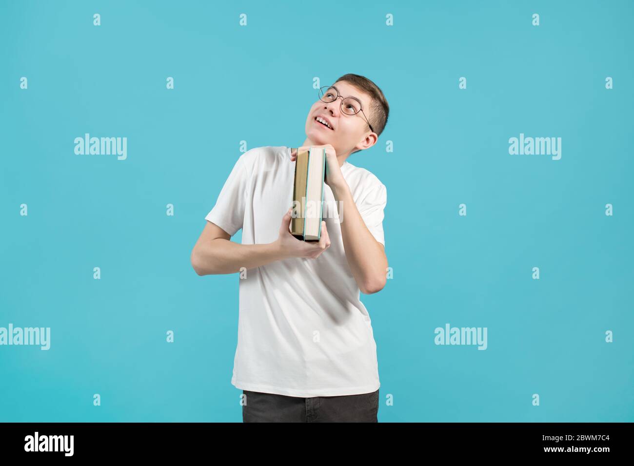 nerd holding books in his hands and smiling looking up Stock Photo