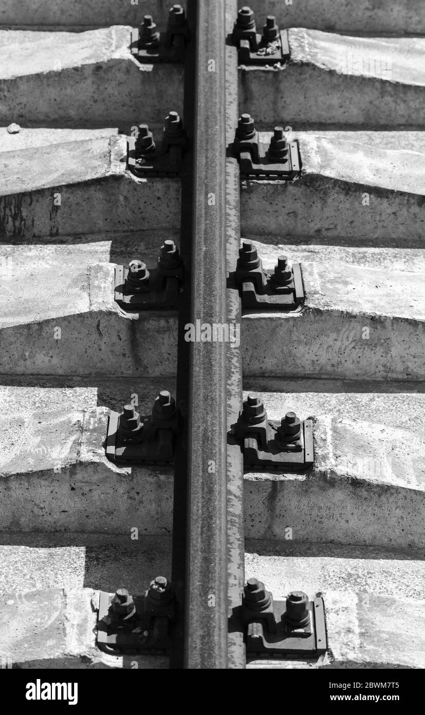 Rusty rail on concrete sleepers. Vertical black and white photo background Stock Photo