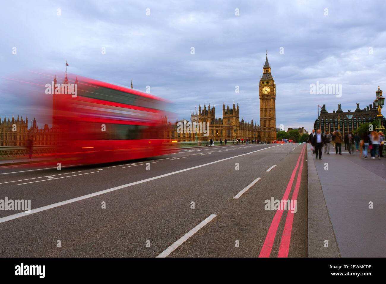 London, UK. Cloudy sky over the city of London, UK. Westminster and Big Ben during the day. Red bus on the bridge, motion blurred people Stock Photo