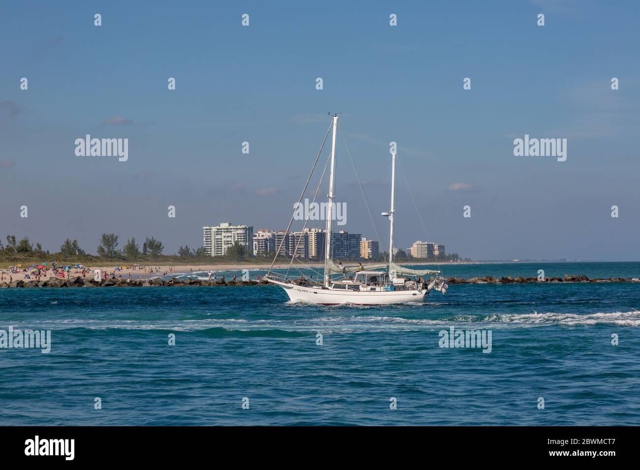 The sailboat 'Slip Away' passes the jetty and into the Fort Pierce Inlet in St. Lucie County, Florida, USA. Stock Photo