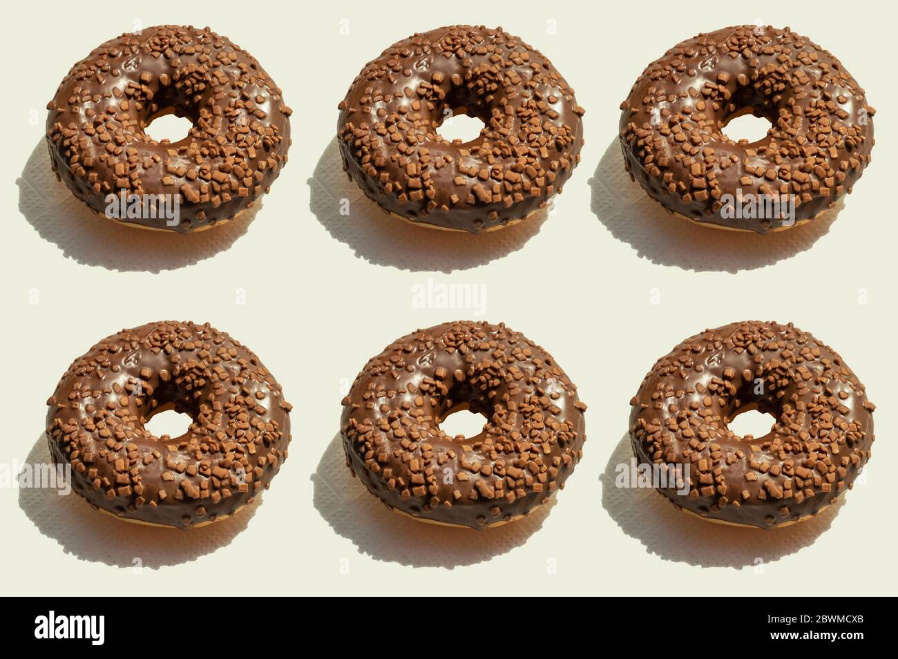 Art food creative pattern with six chocolate donats with shadows on light background. Trendy geometrical design idea, food concept. Two lines of Stock Photo